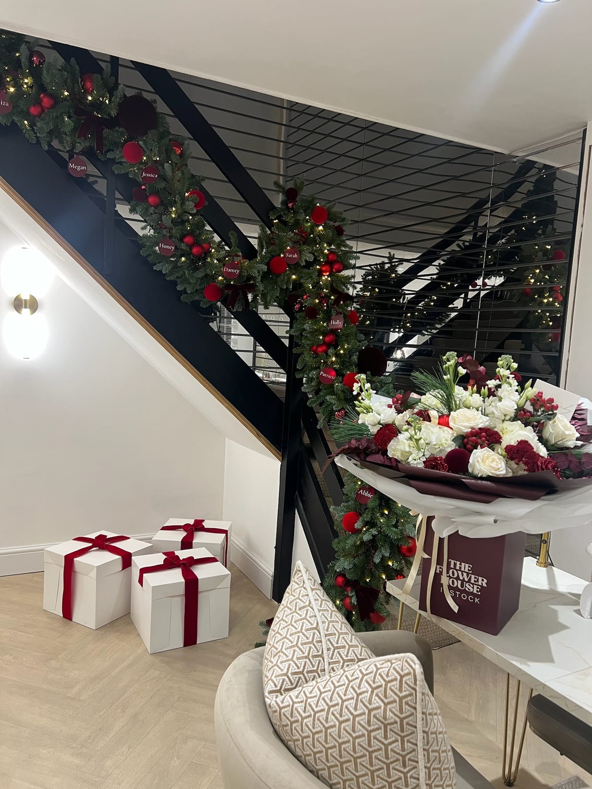 Staircase banister dressed with lit garland, red baubles and personalised name tags.