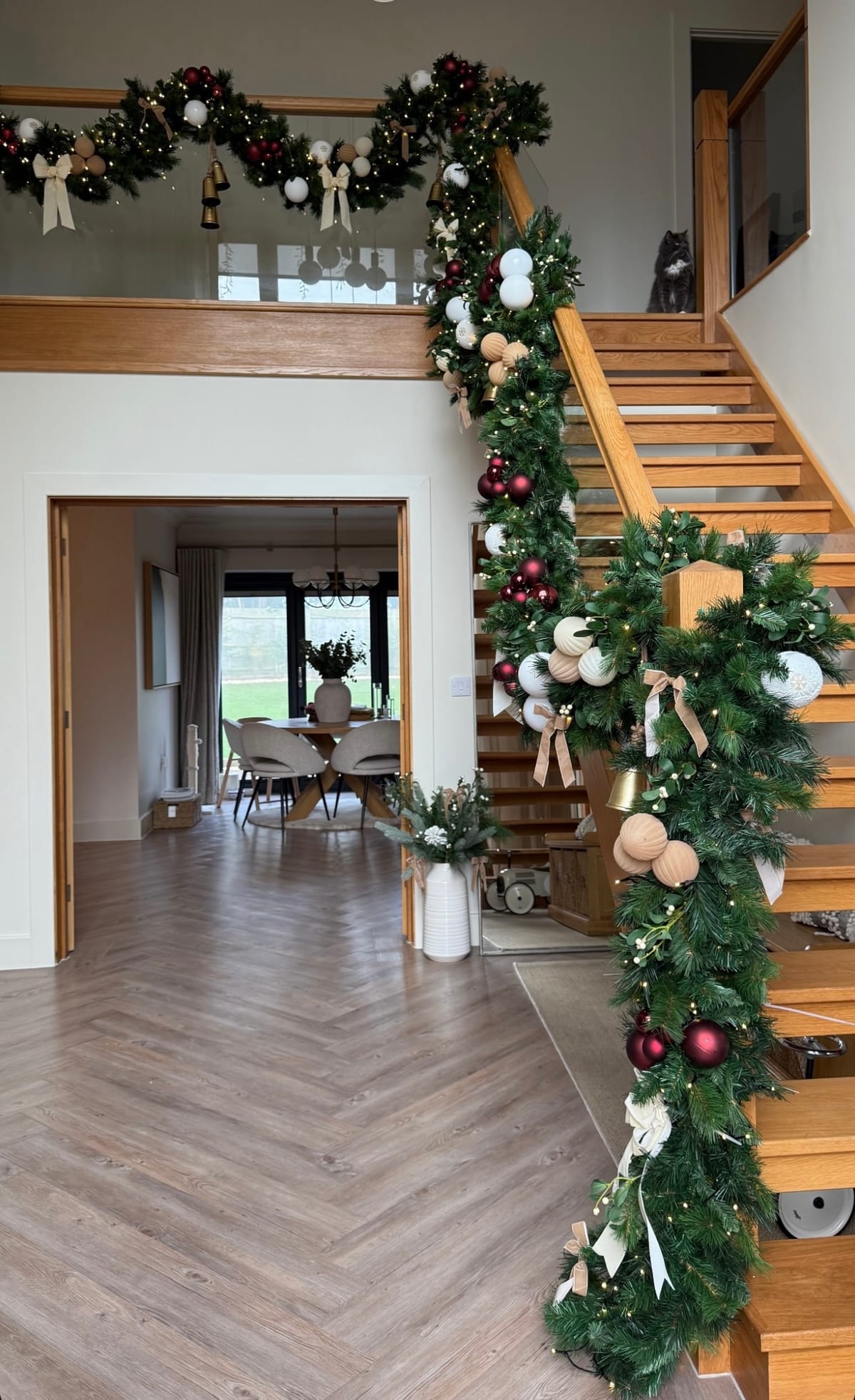 Hallway staircase dressed with garland in burgundy, cream and gold.