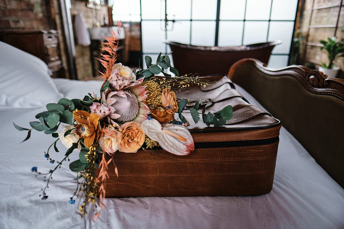 Arrangement of peach roses, dried seed heads and eucalyptus styled on a wooden bench.