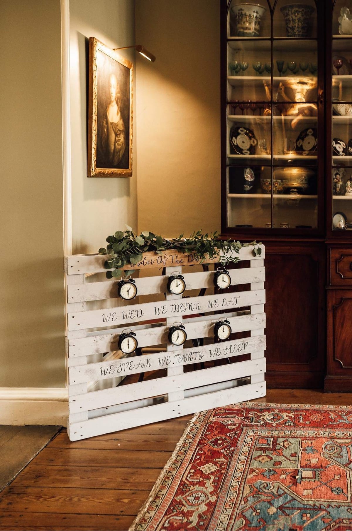 White display unit dressed with foliage and hanging cards in a panelled room.