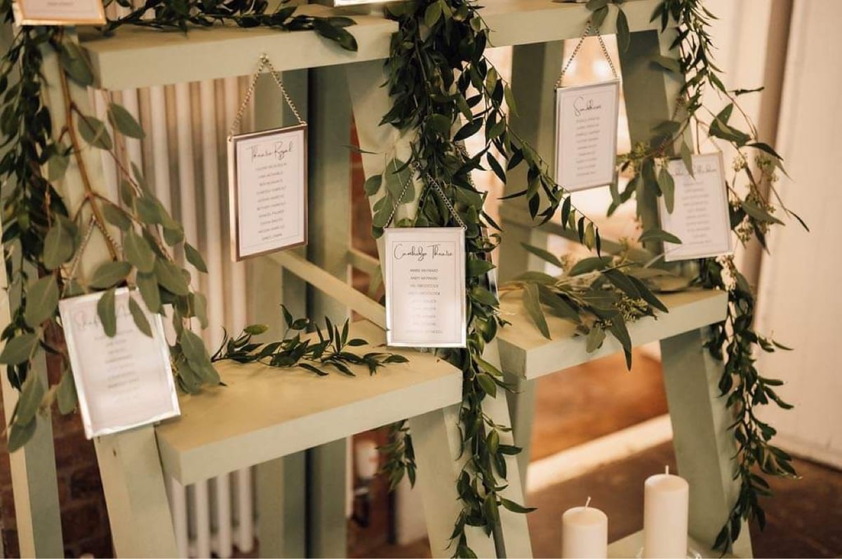 Wider view of a table plan display dressed with trailing eucalyptus and foliage.