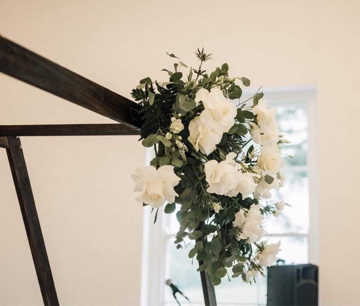 White roses and eucalyptus fixed to the corner of a dark ceremony frame.