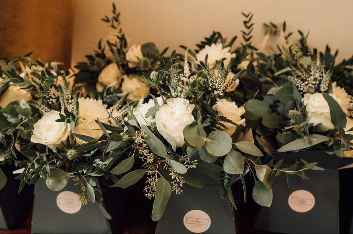 Row of black boxes planted with white roses and eucalyptus.