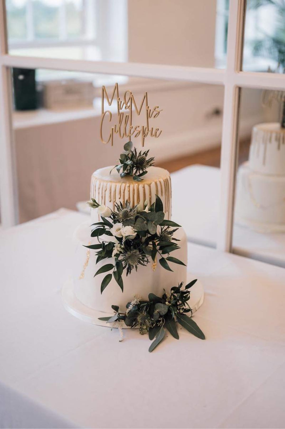 Tiered wedding cake decorated with foliage and white flowers.