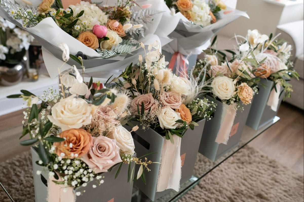 Row of bridesmaid bouquets in cream and peach, boxed and ready for delivery.