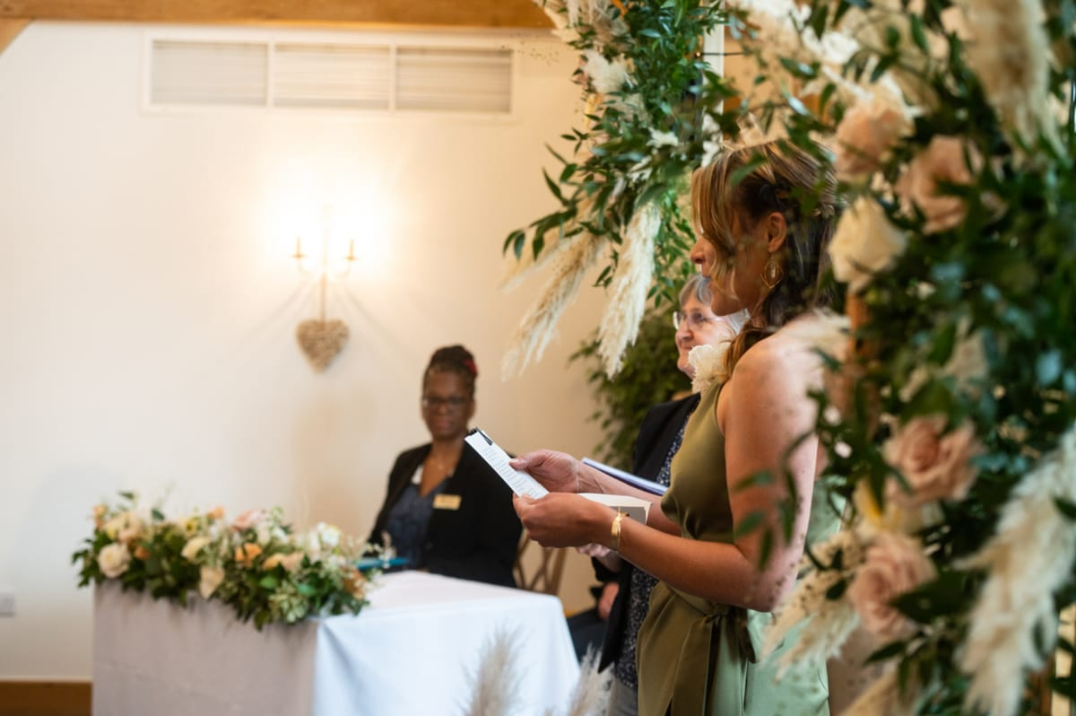 Reading taking place beside a tall arrangement of roses and dried grasses.