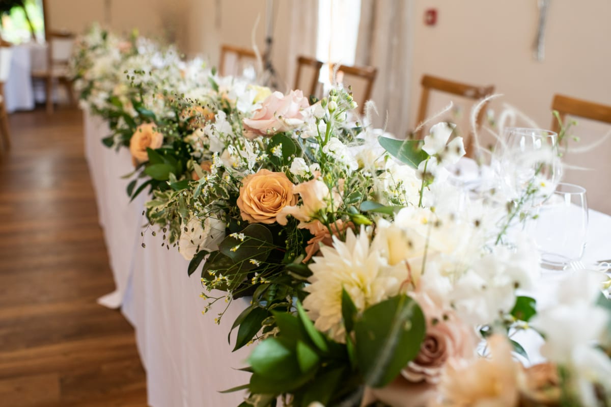 Close view of top table flowers in peach and cream with trailing foliage.